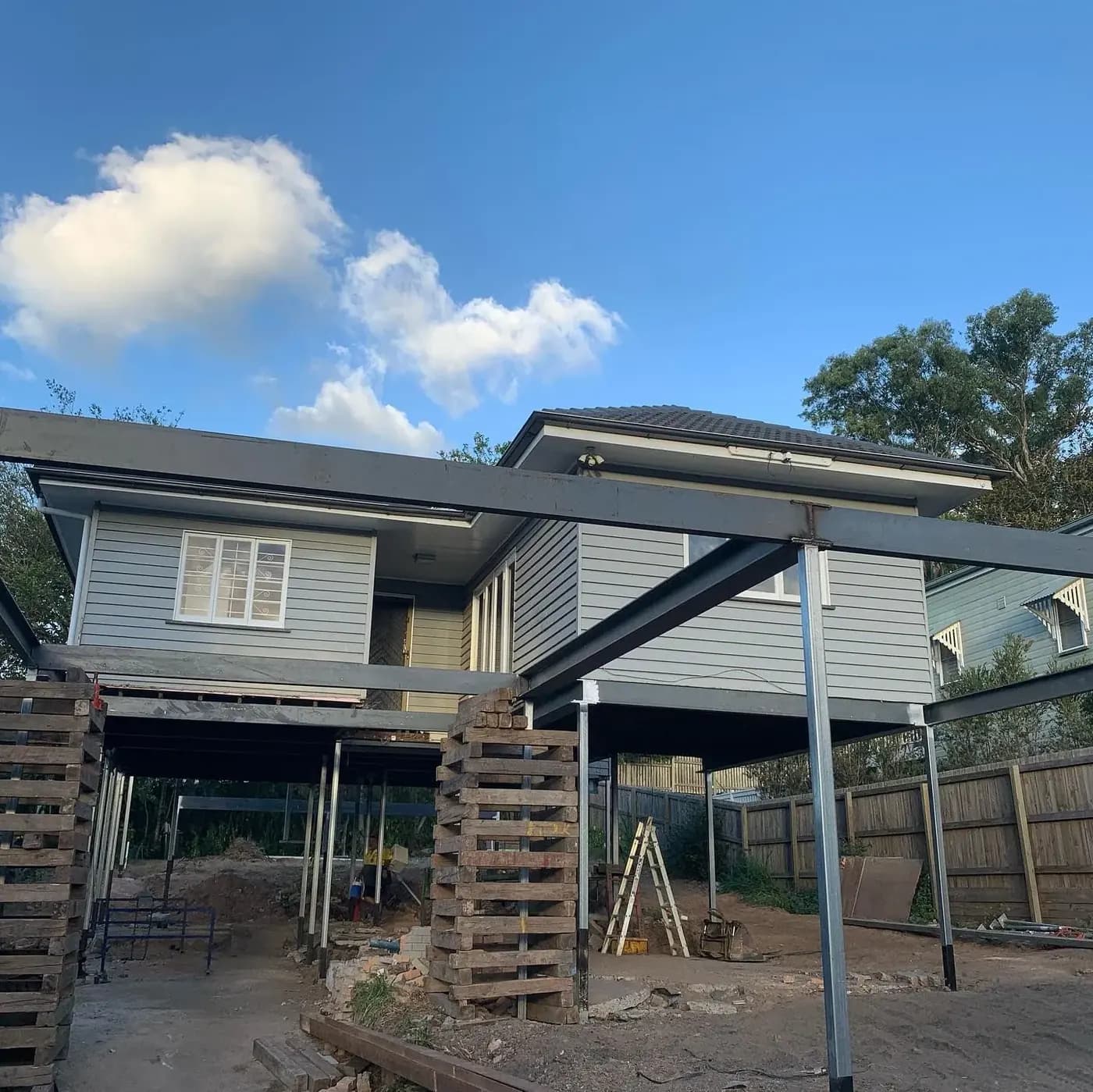 Queenslander home lifted on hydraulic jacks during a house raise